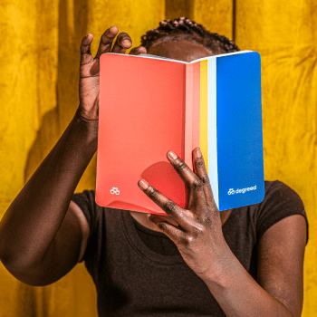 A person reading a book with Degreed colors on the cover